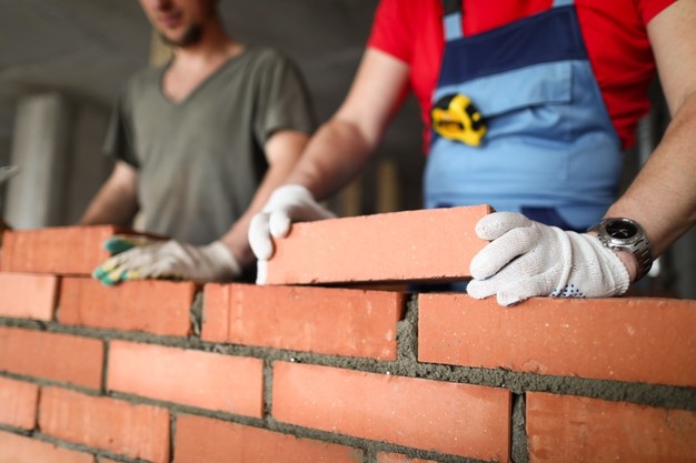 close up of builder laying brick with professional workmen at work bricklayers building wall contractor and worker 151013 14211